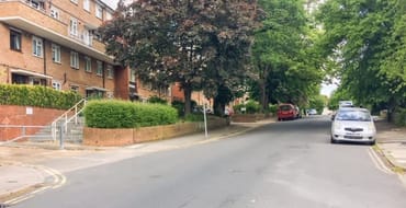 Leafy residential street with a mixture of council flats and houses