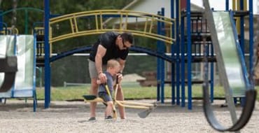 a father and son playing on a digging toy.