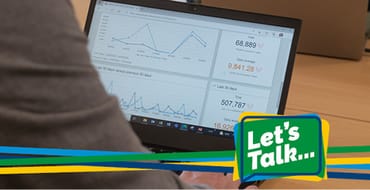 A closeup of a person's arm and laptop that has some graphs on the screen.