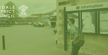 Man walking towards Malton train station next to an information sign