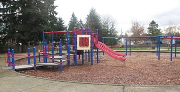 An aging red and blue playground structure at Bella Vista Park