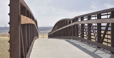 Pedestrian bridge with metal railings extending across an open landscape near Laramie, Wyoming.