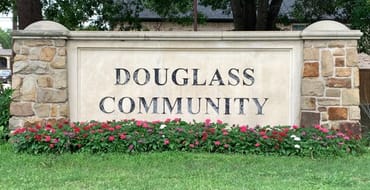 A photo of the Douglass Community entrance sign surrounded by flowers.