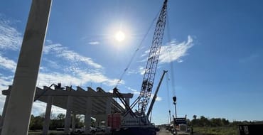 Construction trucks and construction taking place on gray bridge