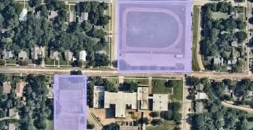 An aerial image of the two distinct park parcels, the track and field to the north of the old Calhoun Middle School Campus, and the tennis court area to the west of the campus. Each parcel is shaded in a transparent lavender. 