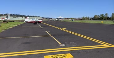An airplane is parked on the runway at Pearson Field. Mount Hood is visible in the background.