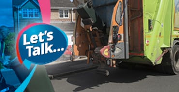 A bin crew worker pushing a wheelie bin toward a waste truck