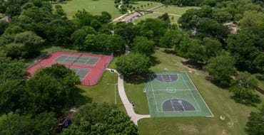 image of basketball courts and tennis courts with green space and green trees all around