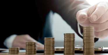 A person in a suit stacks coins. 