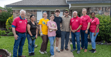 City Council members pose for a photo with volunteers and a female resident outside her home on Love Where You Live service day.