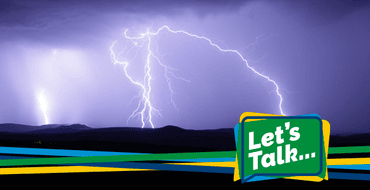 A series of forks of lightening coming from thunder clouds over a dark landscape
