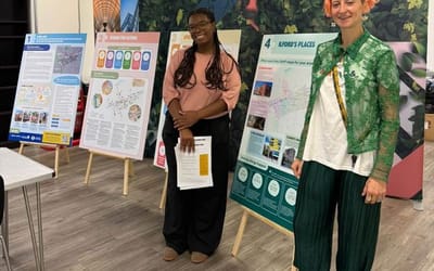Two people standing beside consultation boards displaying the Ilford OAPF proposals at a consultation event.