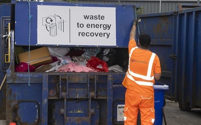 A member of the waste team is putting some rubbish into the household waste recycling centre bin