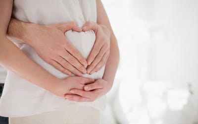 man wrapping arms round pregnant woman
