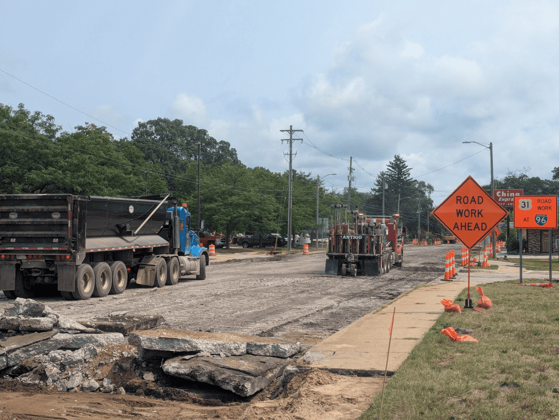Road construction crews use heavy equipment to break up and remove old concrete pavement on Getty Street. Construction barrels and road work signs line the roadway, with exposed pavement and debris visible in the foreground.