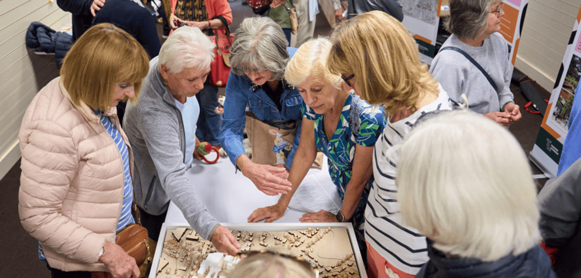Image of people surrounding a model of the development at the 2024 Public Exhibition