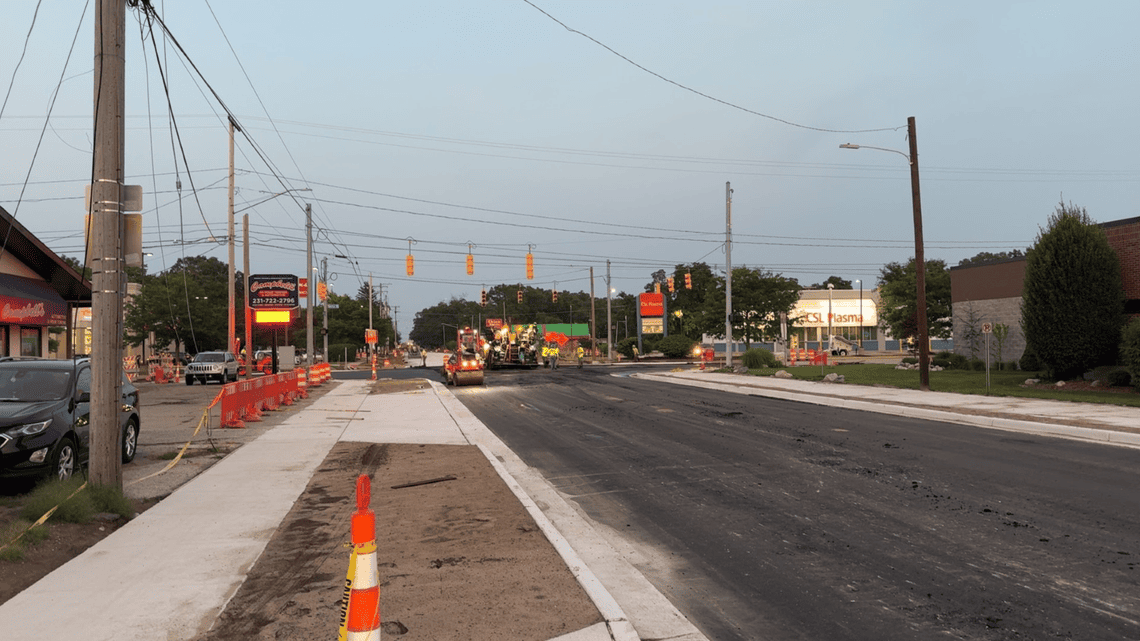 Newly paved roadway at the Getty Street intersection, with construction crews and equipment working farther down the street and new sidewalks along the roadside.