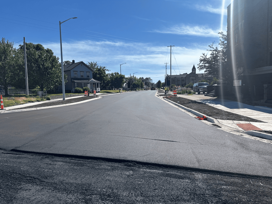 Newly paved section of West Muskegon Avenue with new curbs, sidewalks, and streetscape improvements following reconstruction.