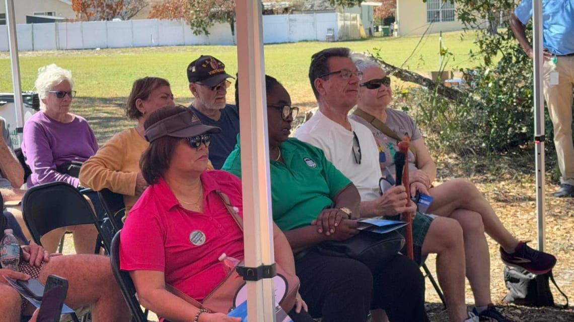 A group of north Tampa residents sit under a tent while listening to the design and construction team.