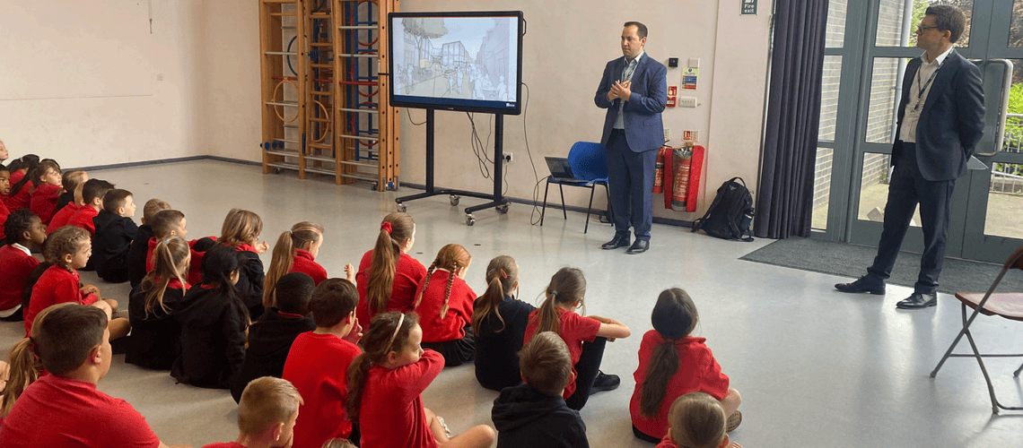 Image of two people presenting the Swan Centre proposals to room of primary school children