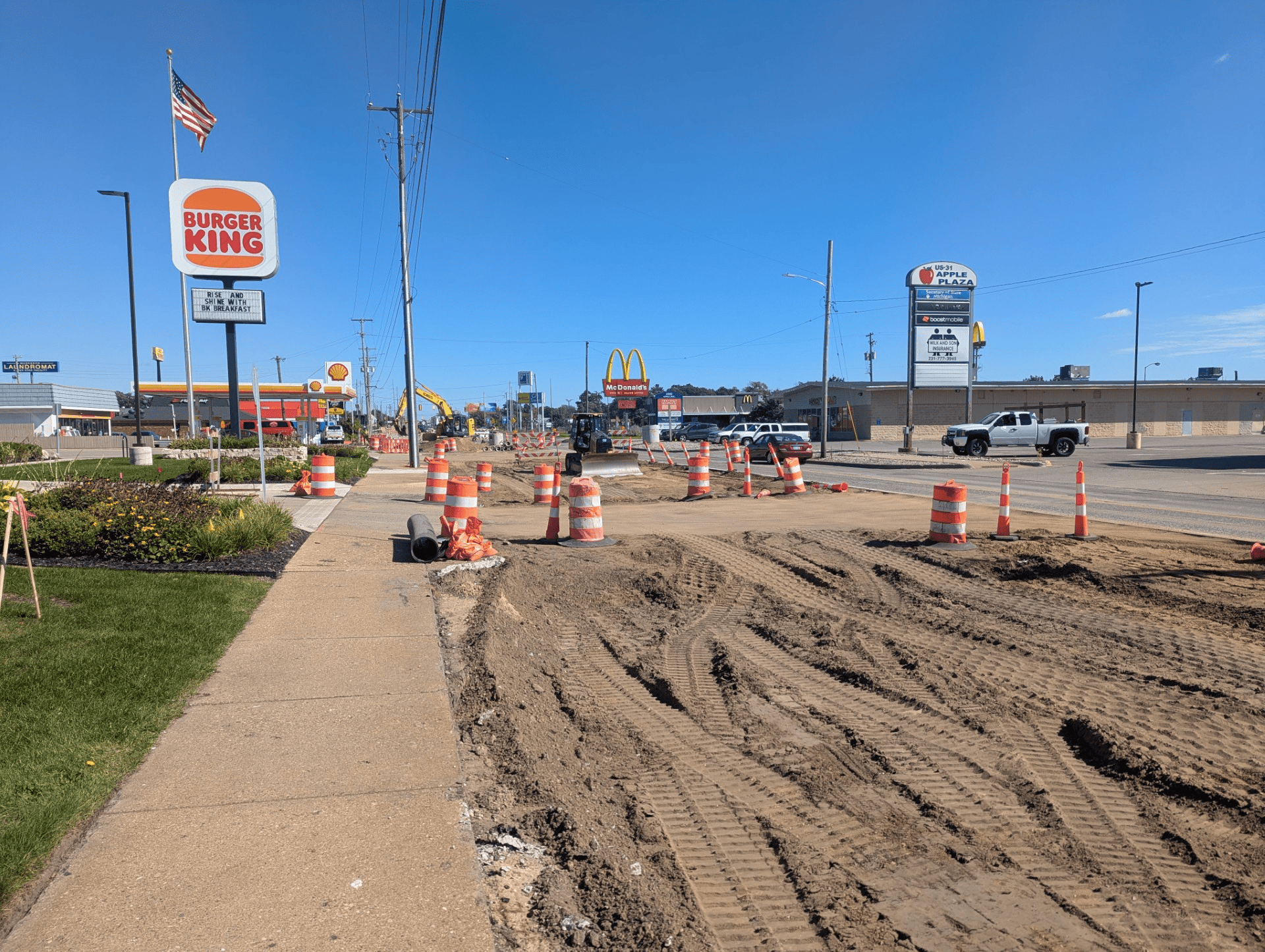 Road construction on Apple Avenue near Home Street, with the roadway excavated and construction barrels marking the work area.