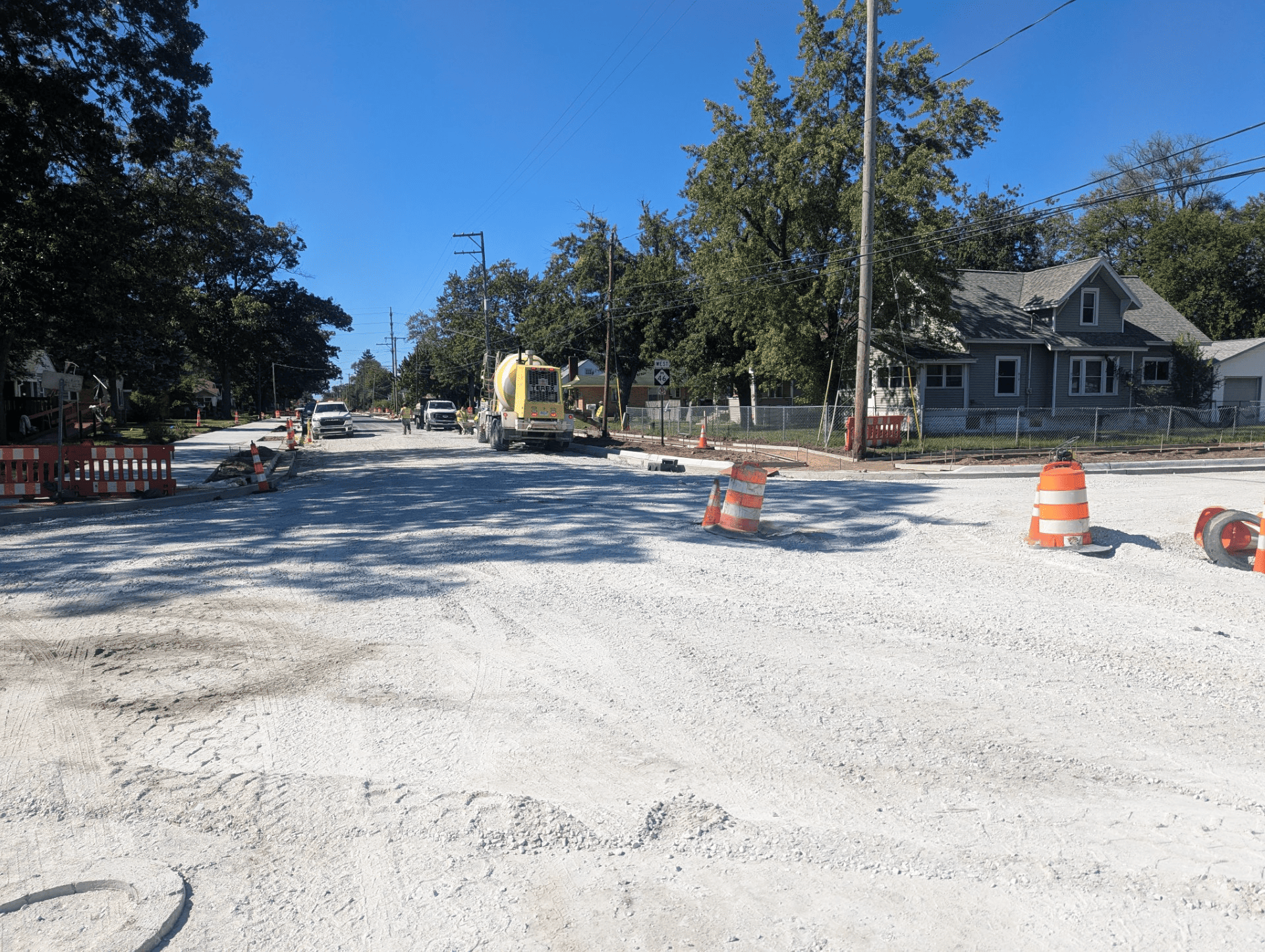 Newly poured concrete sidewalk along Oak Grove as part of the roadway reconstruction project, with construction barriers and equipment nearby.