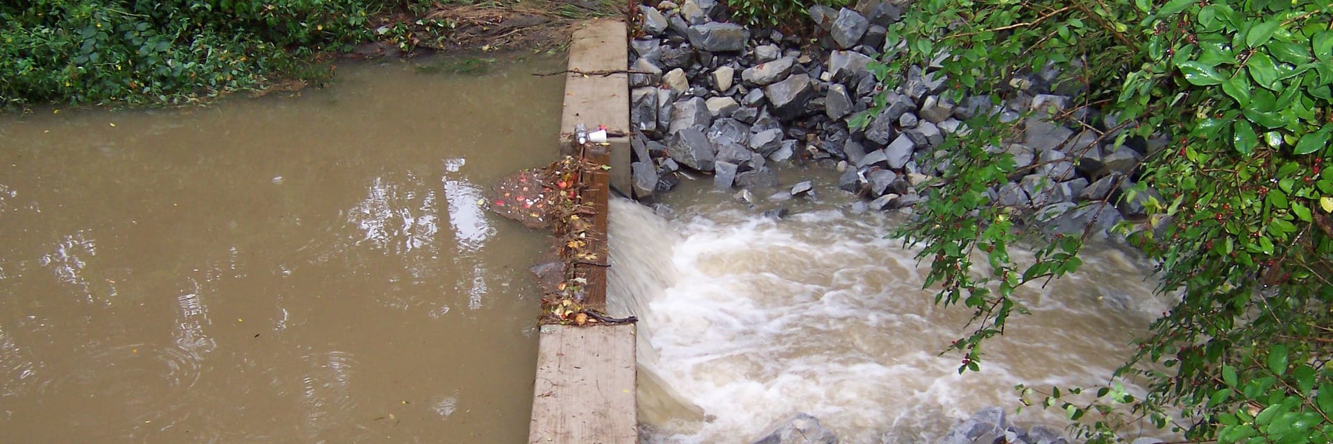 Photo of a stormwater water flowing through a constructed check dam. 