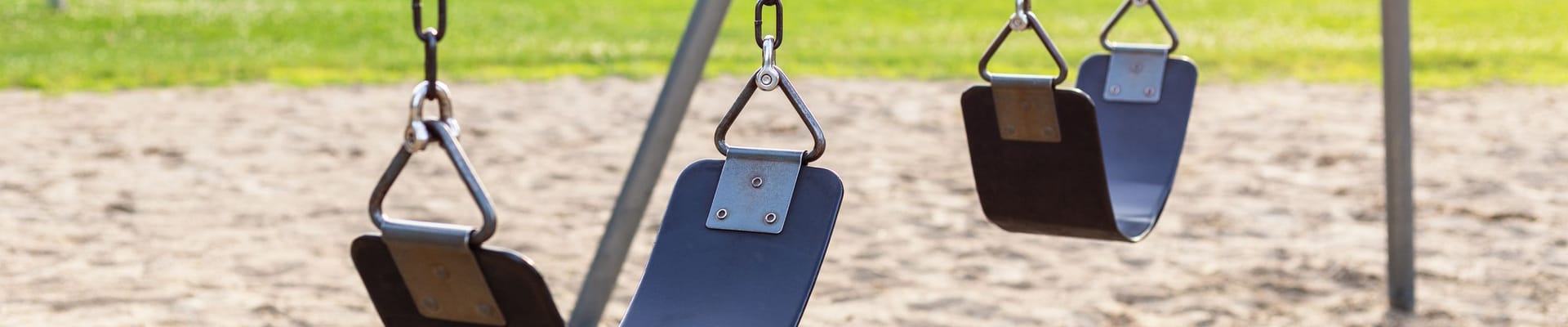 Playground for children with swings in the public park during sunset.