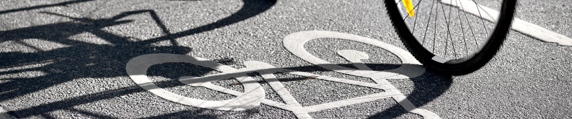 Cyclist riding in a designated bike lane, with a bicycle symbol painted on the pavement.