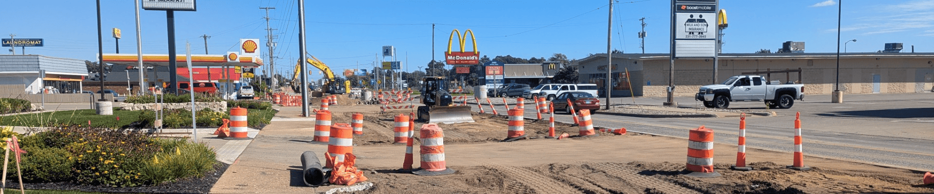 Road construction on Apple Avenue near Home Street, with the roadway excavated and construction barrels marking the work area.