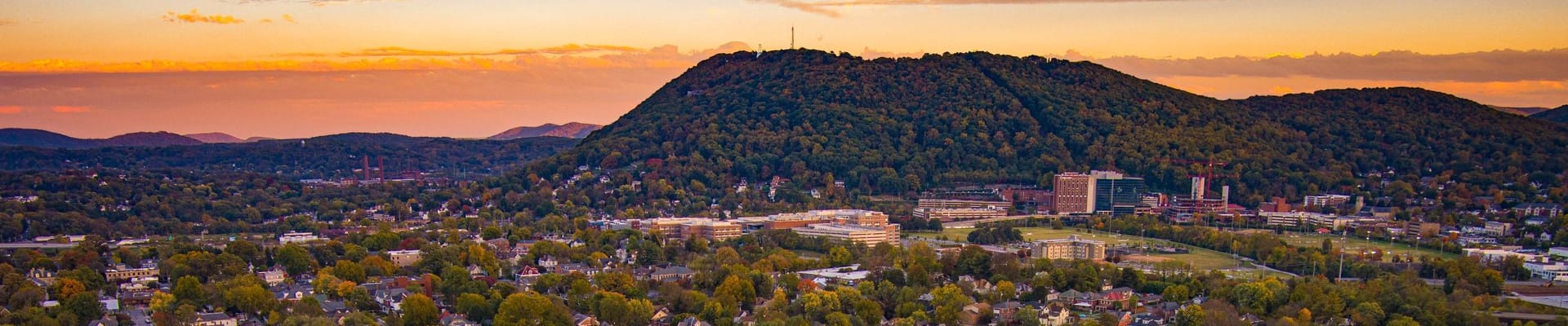 Horizonte de la ciudad de Roanoke con la montaña Mill y el cielo anaranjado al fondo.