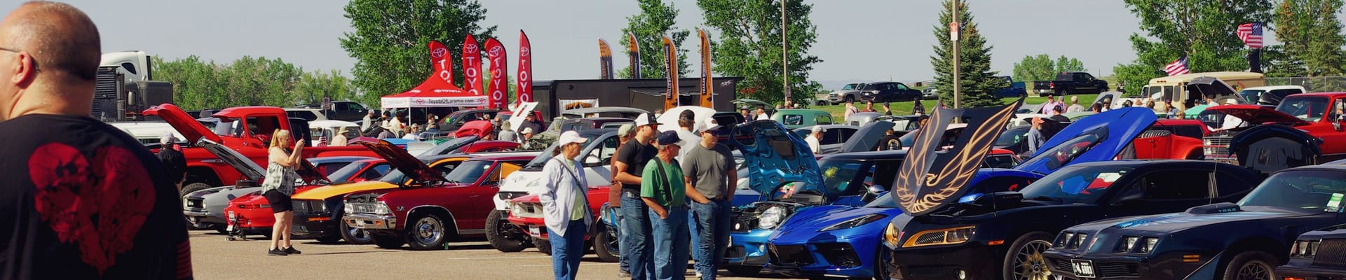 Crowd viewing rows of colorful cars at an outdoor car show in Laramie.