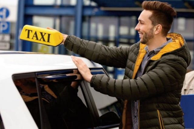 A man holding a taxi roof sign
