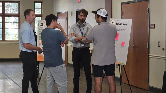 Image of three attendees chatting with a City staff member