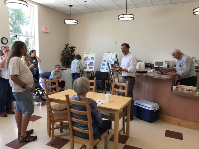 Many people gathered around a table doing public outreach.