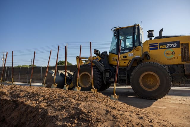 shovels in dirt with excavator in background
