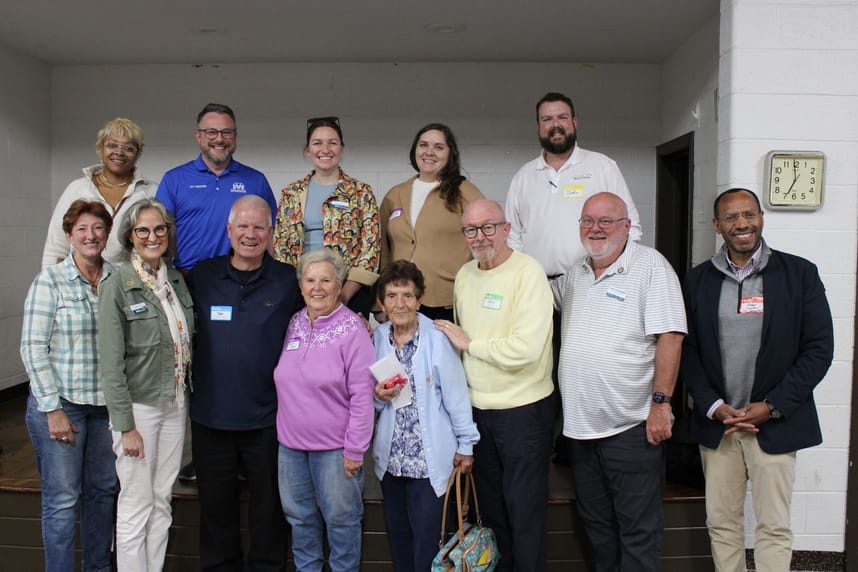 A group of community members and local leaders pose together for a photo following a community planning session.