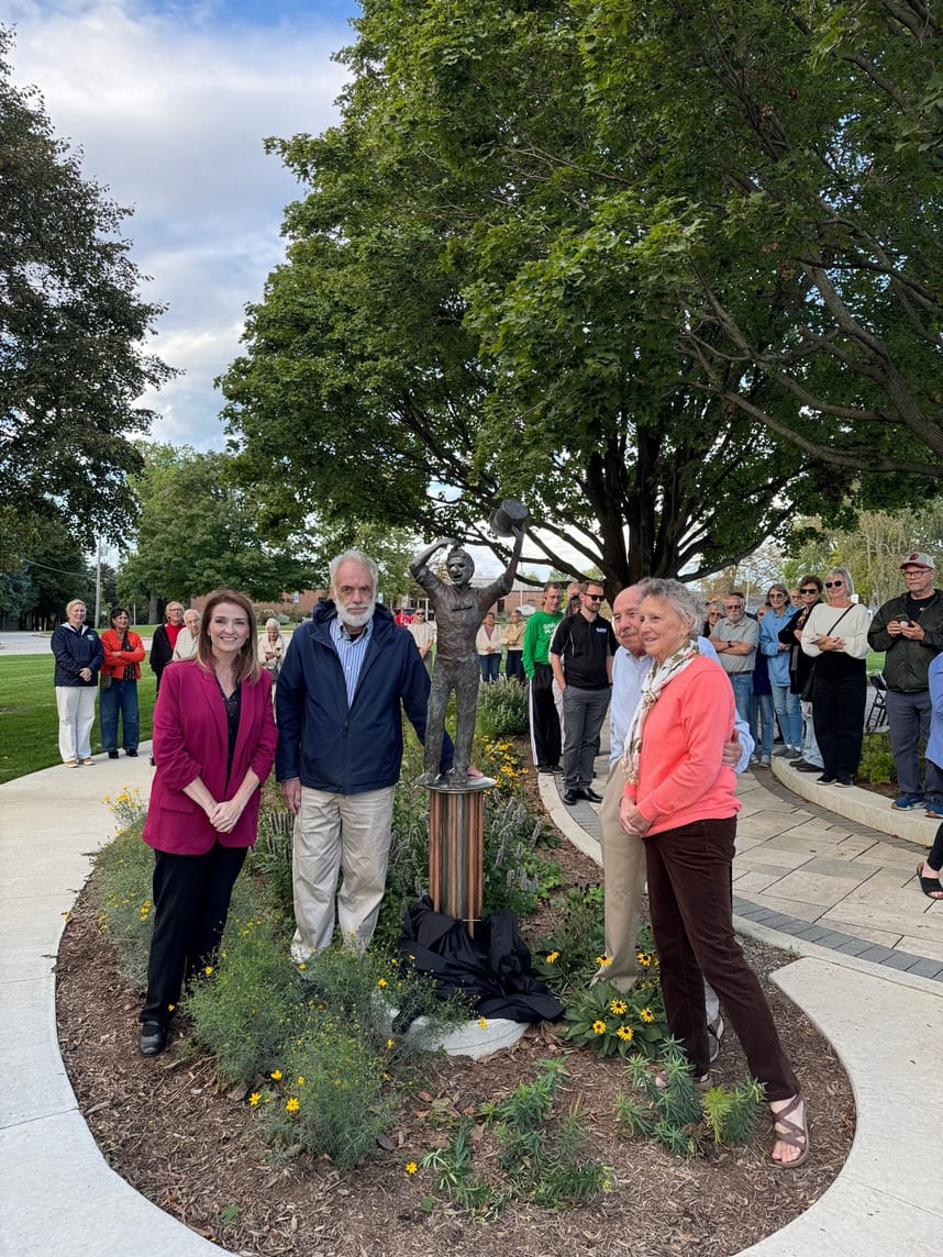 Four people surrounding a sculpture. 