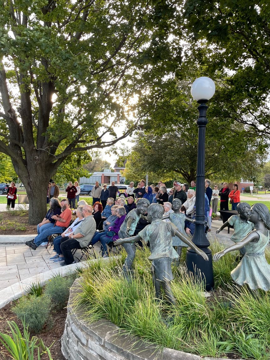 People sitting on folding chairs in a sculpture park