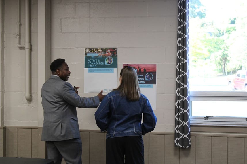 Two people discuss community vision posters displayed on a wall during a planning session.