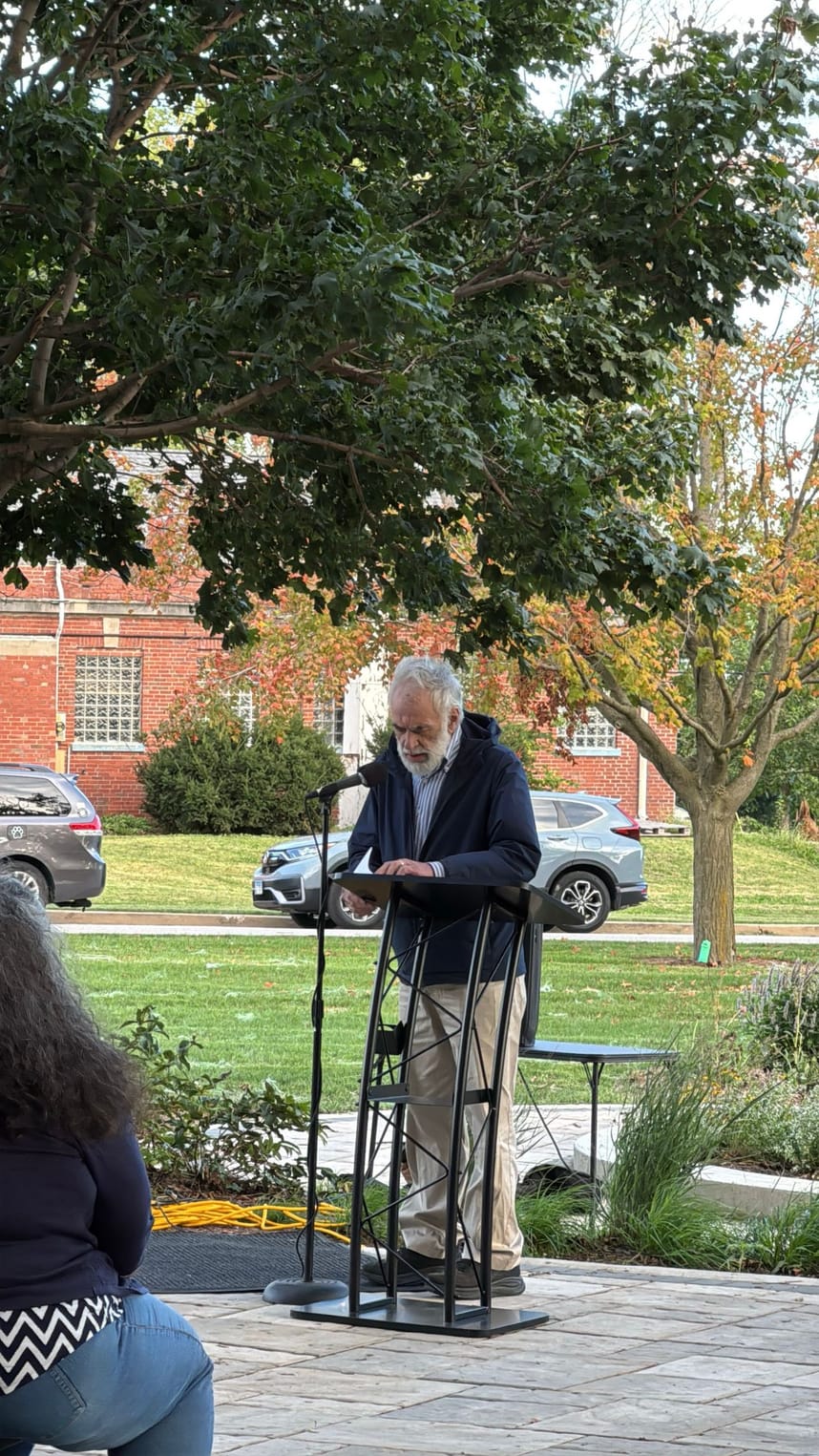 A man speaking into a mic to a crowd of people