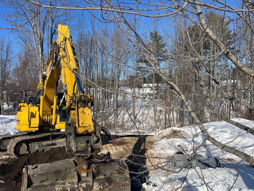 Operator spreading loam over new storm drain outfall