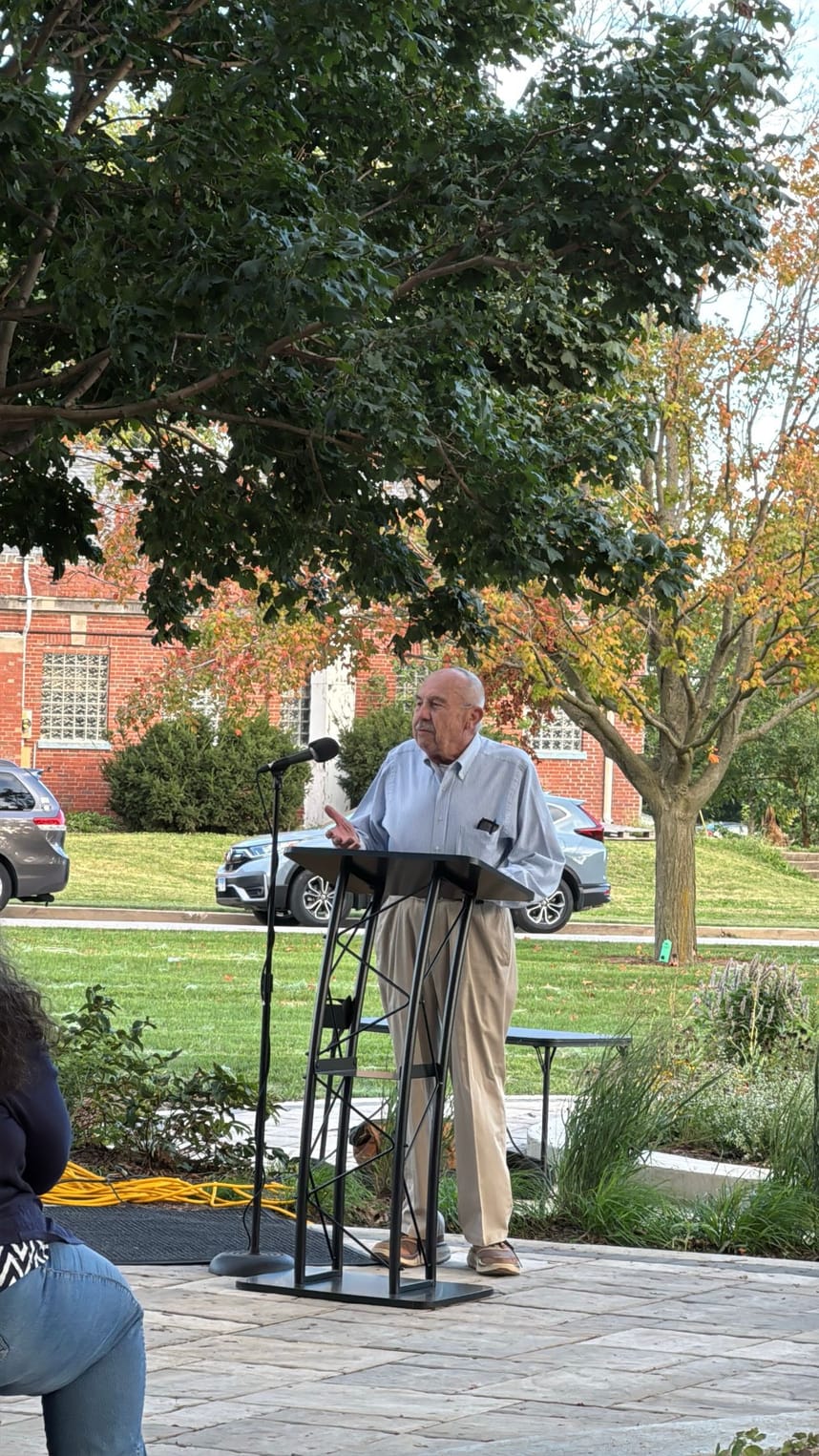 A man speaking into a mic to a crowd of people