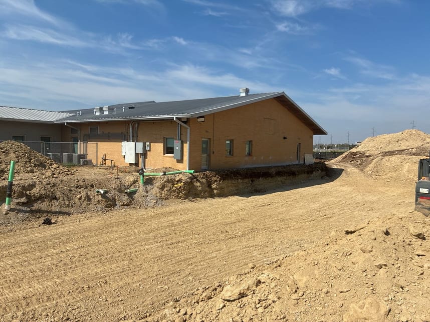 Existing building, with large excavation hole made for foundation.