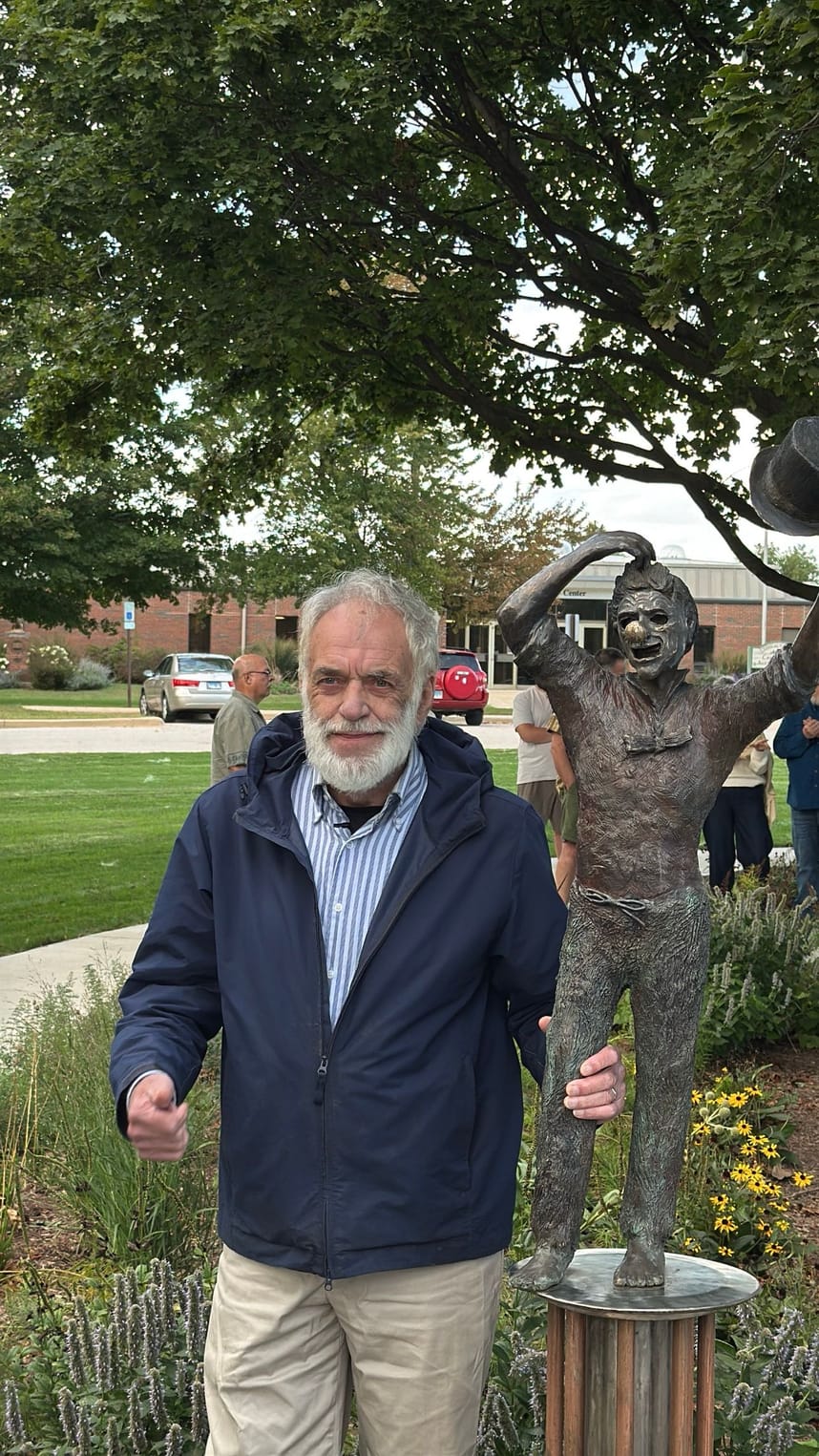 A man standing next to a sculpture. 