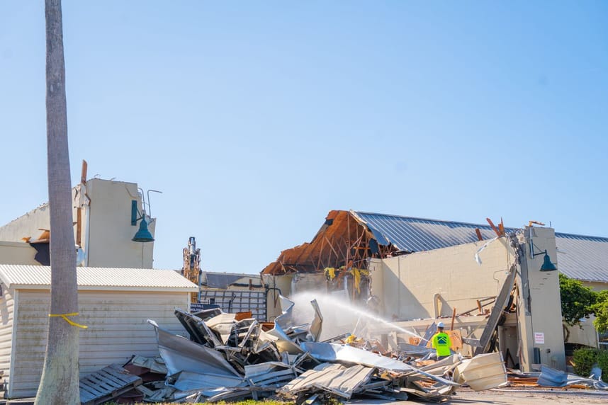 Building being turn down with large pile of debris in front of it