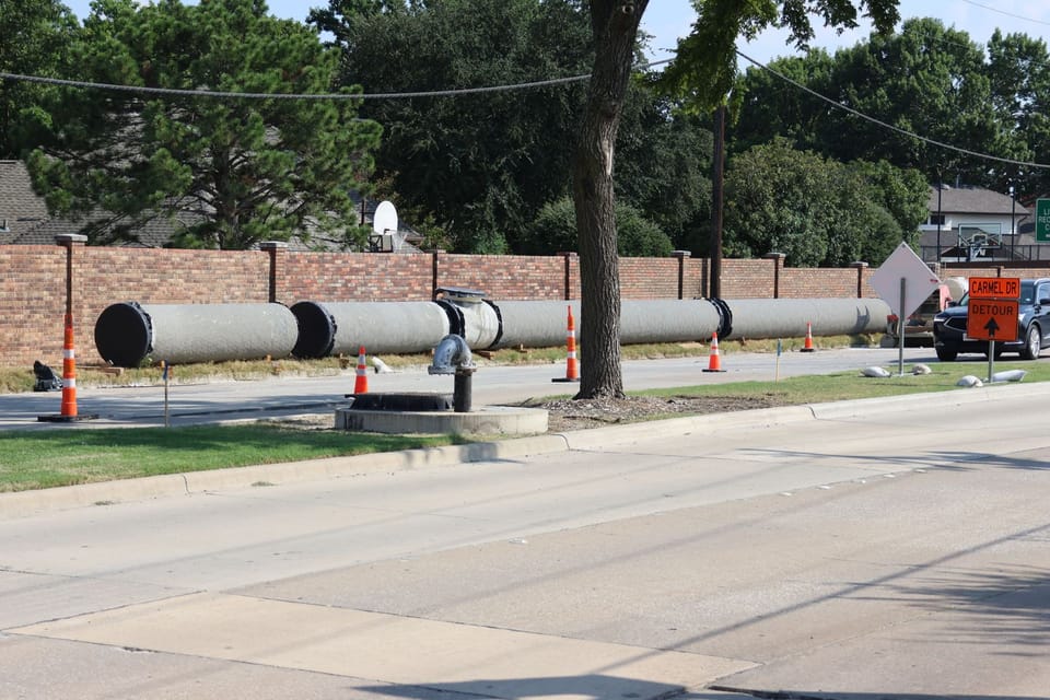Large concrete waterlines in the grass median of Custer Road.