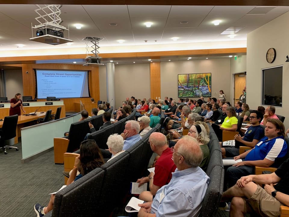 Photo of people in Council Chambers watching June 27, 2023 public meeting presentation. 