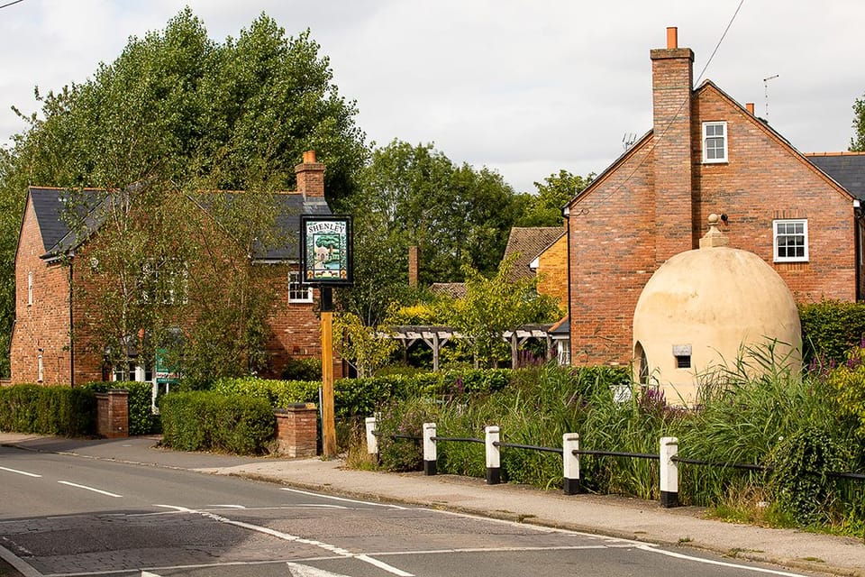 A amllscale modern housing development in Shenley, adjoining the village pond and historic Shenley Cage, a small domed structure formerly used as a lockup.