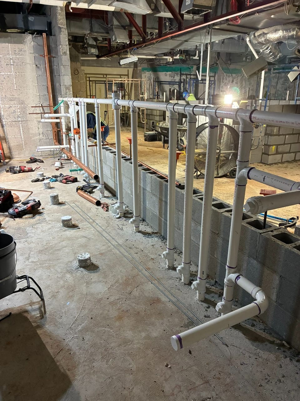 photo of new plumbing equipment in front of a concrete wall during renovation of a pool locker room